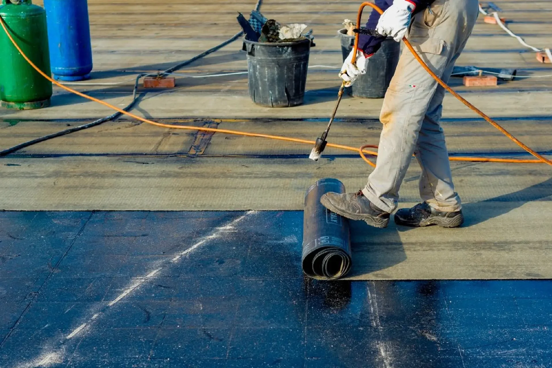 A worker applying waterproofing membrane on a roof surface.