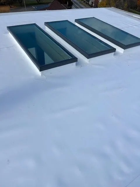Three rectangular skylights on a snowy rooftop under a clear sky.